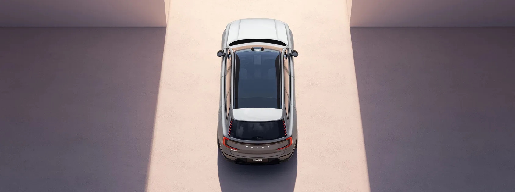 Vista superior de SUV eléctrica Volvo EX90 siendo conducida por una salida de luz.  
